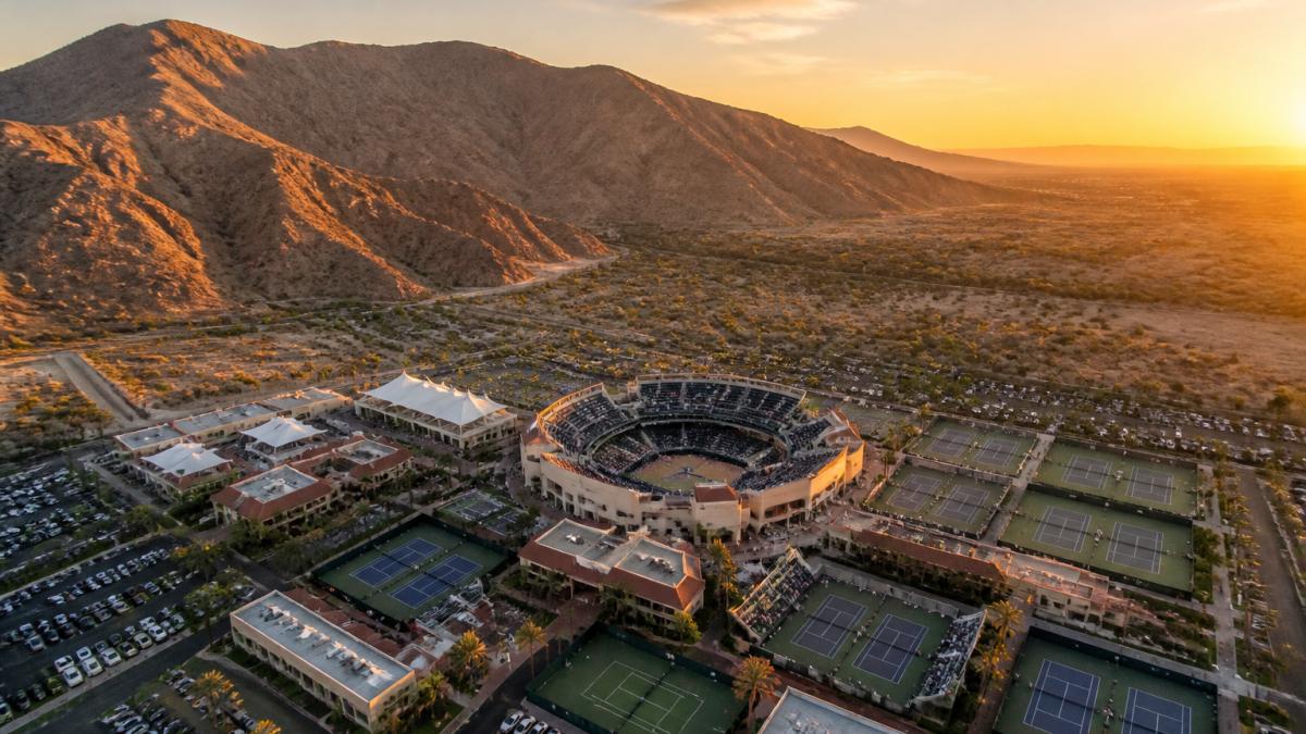Aerial view of the Indian Wells Tennis Garden stadium and surrounding desert landscape at golden hour, with the Santa Rosa Mountains in the background